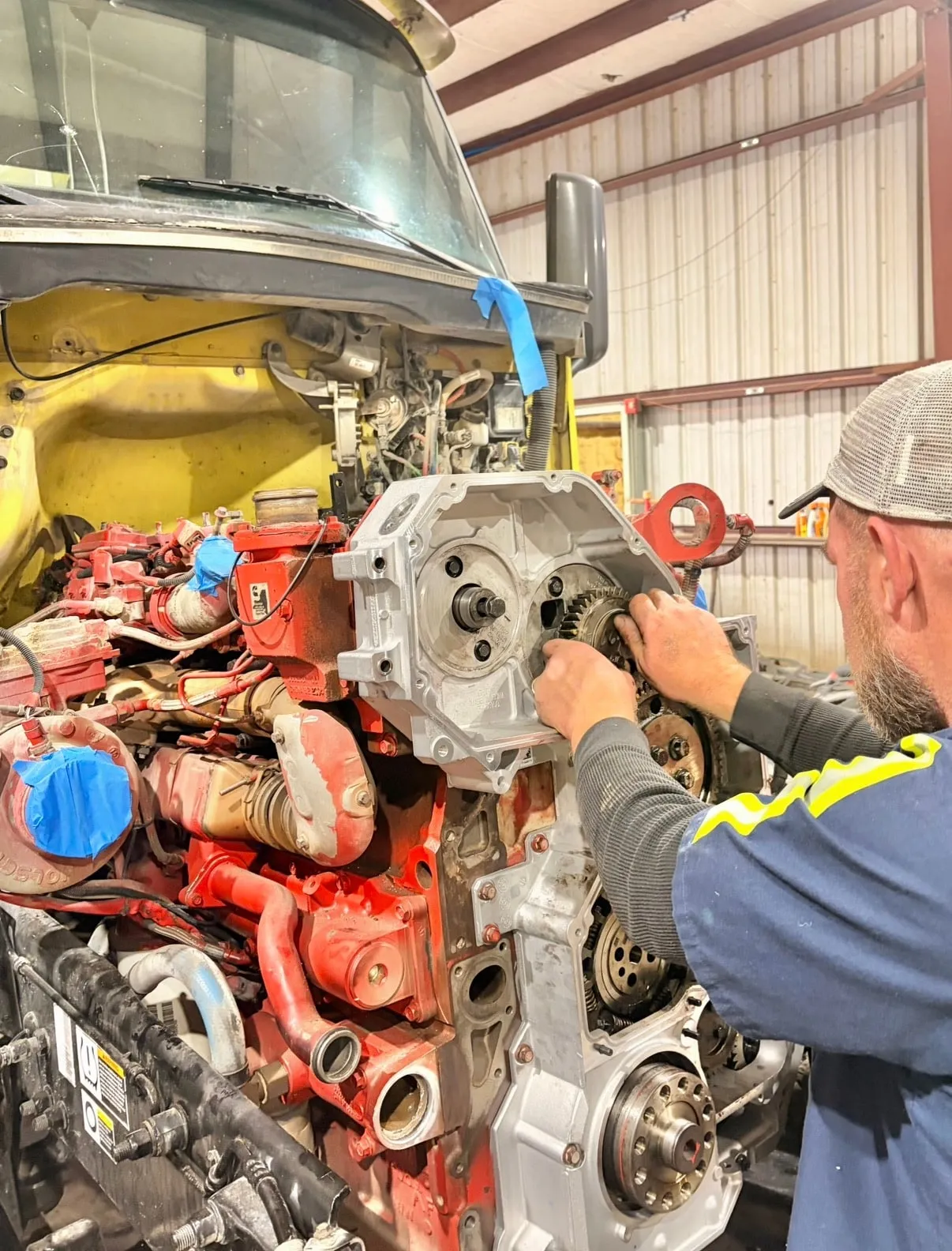 Mark Dugas Jr., owner and lead technician, fitting the front gear housing to a Cummins engine with the cab tilted forward in the Port Arthur shop.